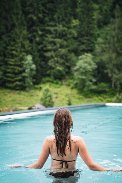 Frau im Infinity Pool blickt ins Grüne im Hotel Tuxertal